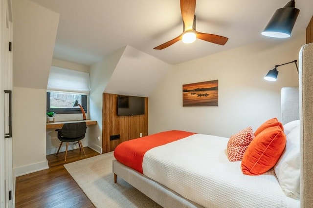 bedroom featuring built in desk, dark wood-type flooring, ceiling fan, and vaulted ceiling