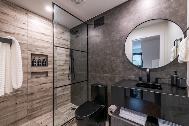 bathroom with tiled shower, sink, and toilet