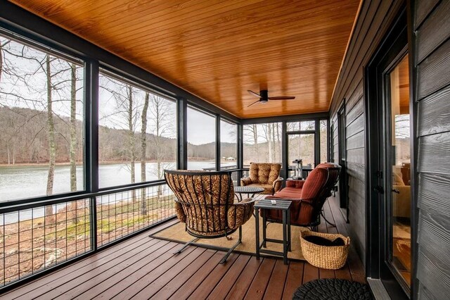 sunroom with wooden ceiling, ceiling fan, and a water view