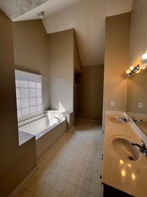 bathroom with a bath, lofted ceiling, and a sink