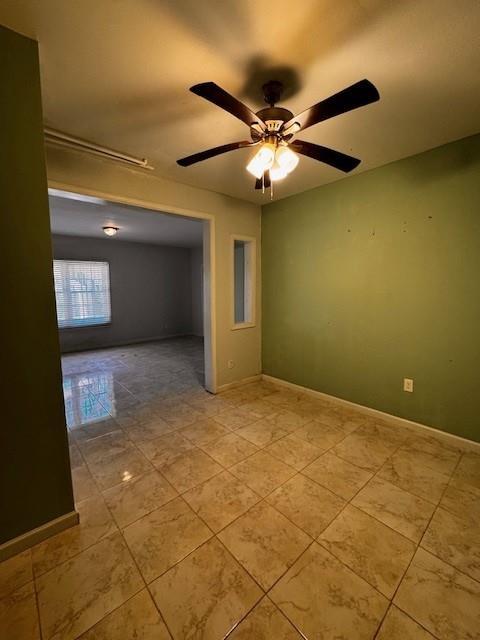 empty room with baseboards and a ceiling fan