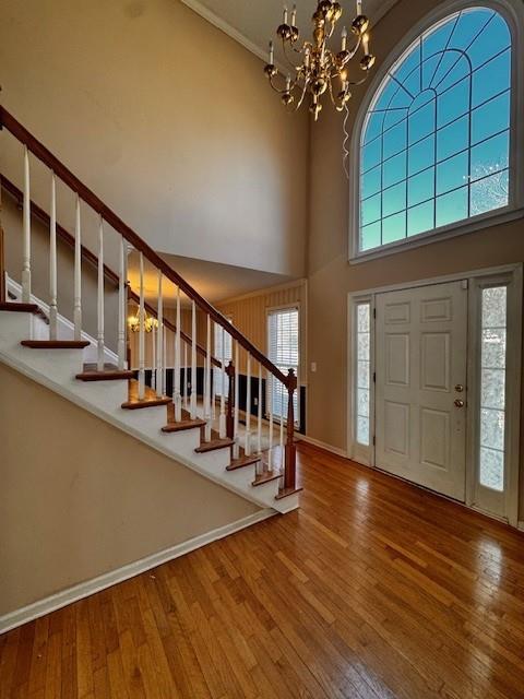 entrance foyer featuring wood-type flooring, an inviting chandelier, stairs, and a healthy amount of sunlight