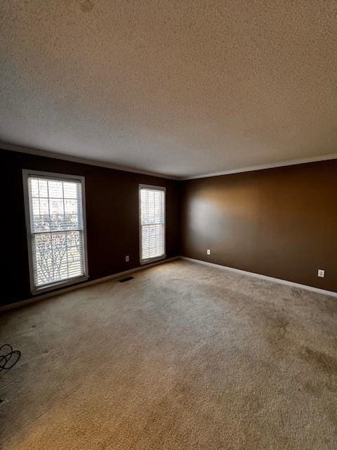 empty room featuring a textured ceiling, light colored carpet, visible vents, and baseboards