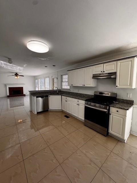 kitchen featuring a peninsula, ceiling fan, stainless steel appliances, under cabinet range hood, and dark countertops