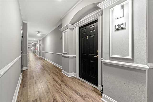 corridor featuring crown molding, baseboards, and wood finished floors