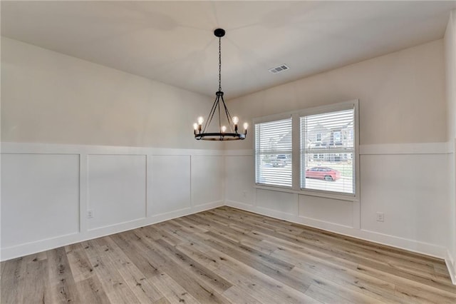 unfurnished dining area featuring a chandelier and light hardwood / wood-style floors