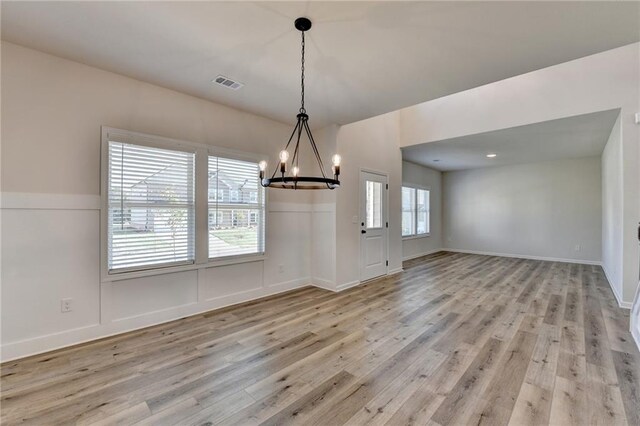 unfurnished dining area featuring light hardwood / wood-style flooring and a chandelier