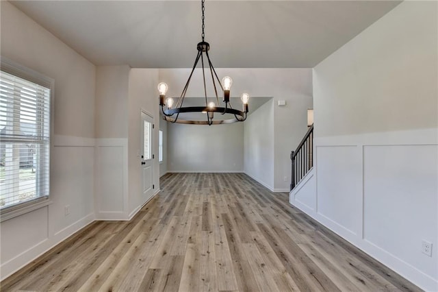 unfurnished dining area with plenty of natural light, light hardwood / wood-style floors, and an inviting chandelier