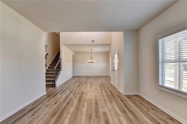 unfurnished living room featuring a chandelier and light wood-type flooring