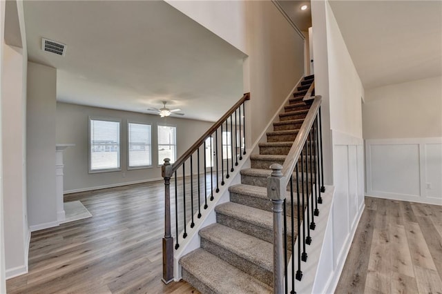 staircase with hardwood / wood-style floors and ceiling fan