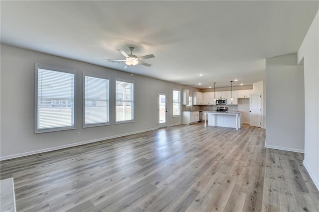 unfurnished living room featuring ceiling fan and light hardwood / wood-style flooring