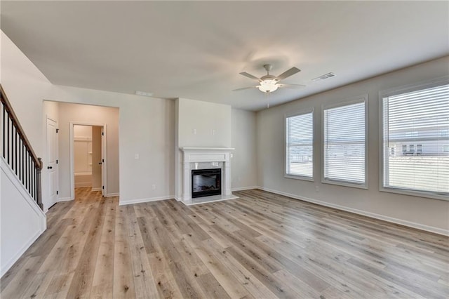 unfurnished living room featuring a wealth of natural light, light hardwood / wood-style floors, and ceiling fan