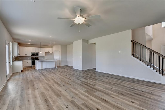 unfurnished living room with light wood-type flooring and ceiling fan