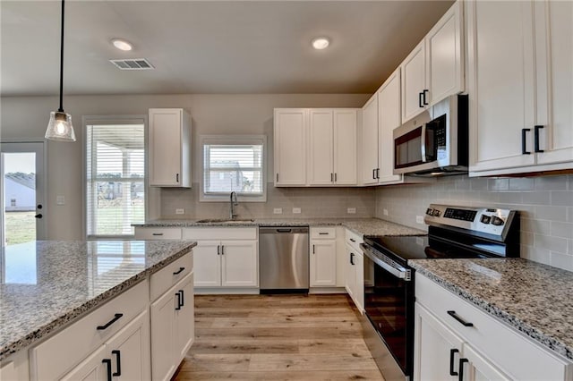 kitchen featuring stainless steel appliances, white cabinetry, sink, backsplash, and light wood-type flooring