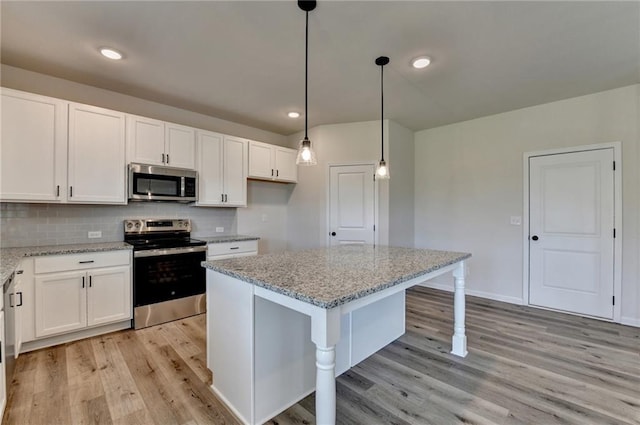 kitchen featuring white cabinets, a kitchen island, light stone counters, and appliances with stainless steel finishes