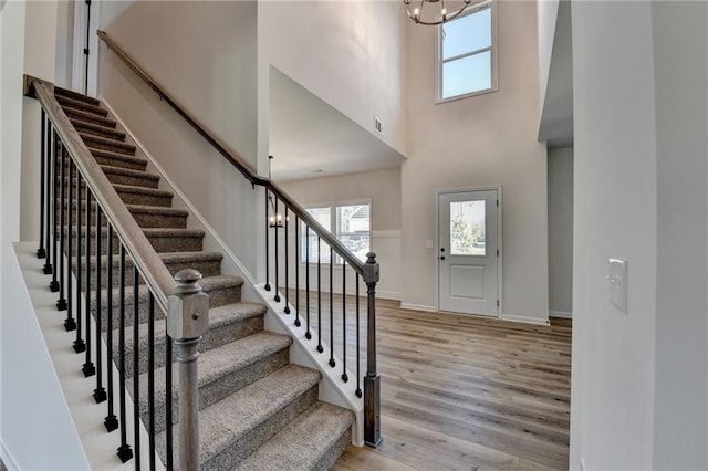 entryway featuring a towering ceiling, light hardwood / wood-style floors, and a chandelier