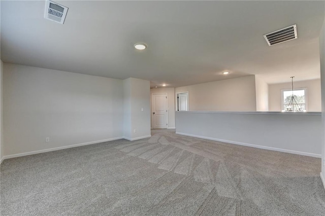 spare room featuring light colored carpet and a chandelier