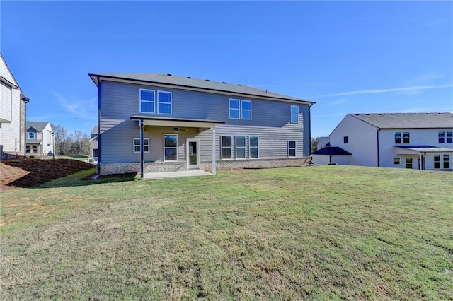 rear view of house with ceiling fan, a patio, and a yard