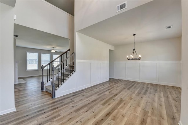 interior space with ceiling fan with notable chandelier and light hardwood / wood-style flooring