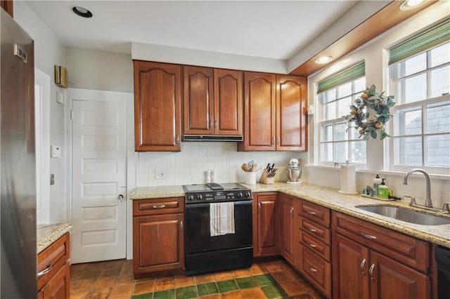 kitchen featuring backsplash, light stone counters, black appliances, and sink