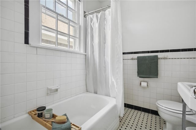 bathroom featuring tile walls, shower / bathtub combination with curtain, tile floors, and toilet