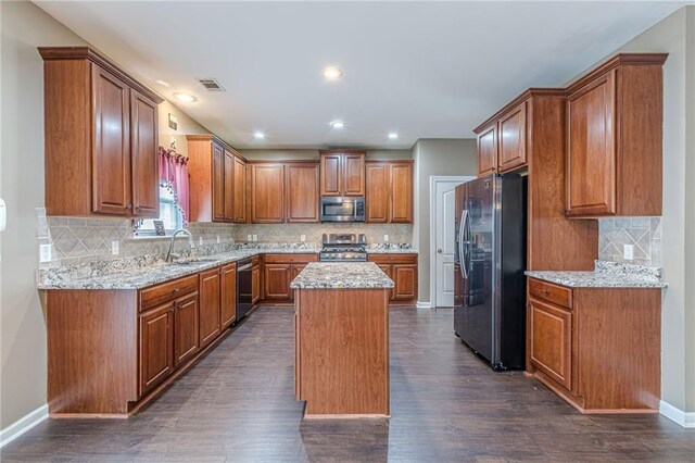 kitchen featuring appliances with stainless steel finishes, dark wood-type flooring, tasteful backsplash, and light stone countertops