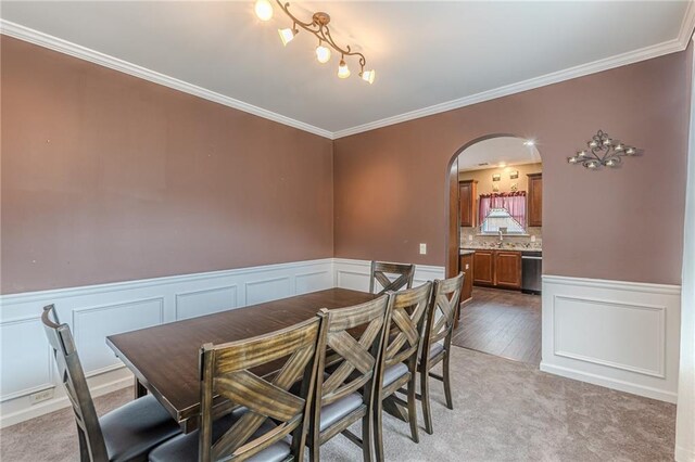 carpeted dining space featuring sink and ornamental molding