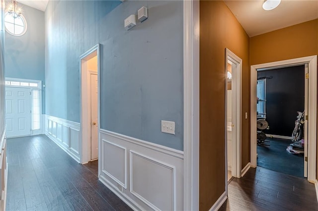 corridor featuring dark wood-style floors and a decorative wall