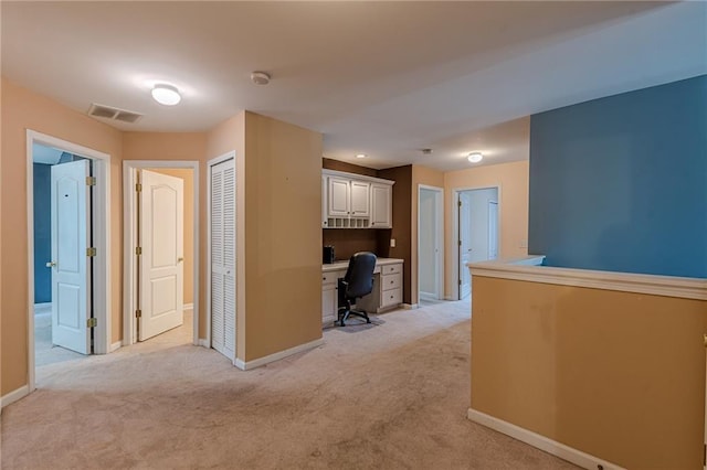 hall with light carpet, visible vents, and baseboards