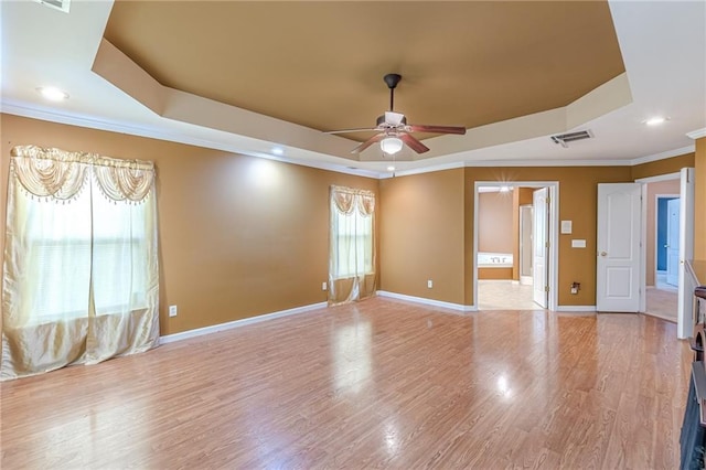 spare room featuring light wood-type flooring, baseboards, visible vents, and a raised ceiling