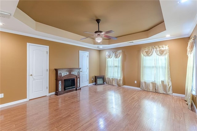 unfurnished living room featuring baseboards, a fireplace, a raised ceiling, and light wood-style floors