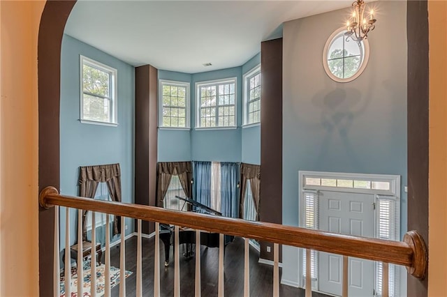 hallway featuring stairway, wood finished floors, and an inviting chandelier