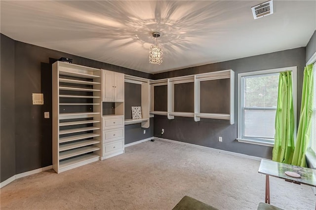 unfurnished bedroom with light carpet, built in desk, visible vents, and baseboards