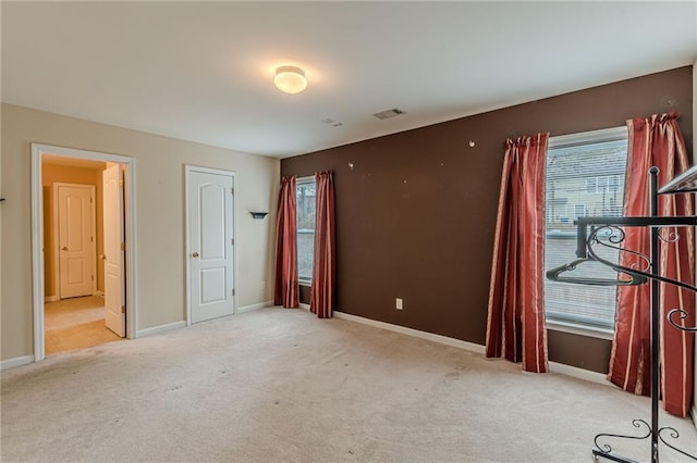 empty room featuring carpet floors, visible vents, and baseboards