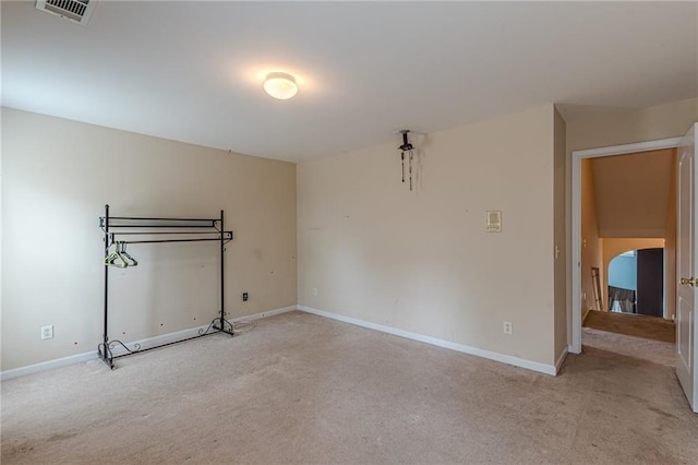 interior space with baseboards, visible vents, arched walkways, and light colored carpet