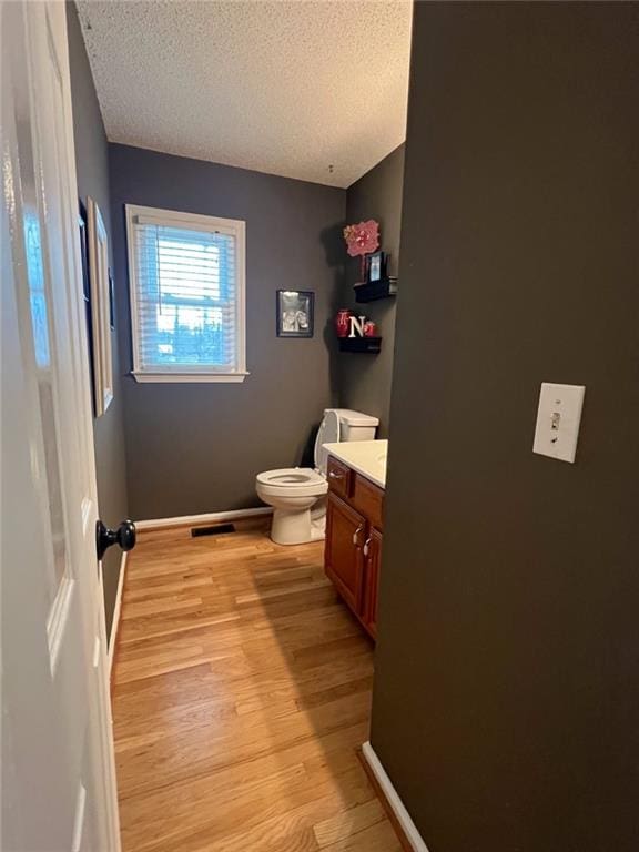 bathroom featuring vanity, toilet, wood-type flooring, and a textured ceiling