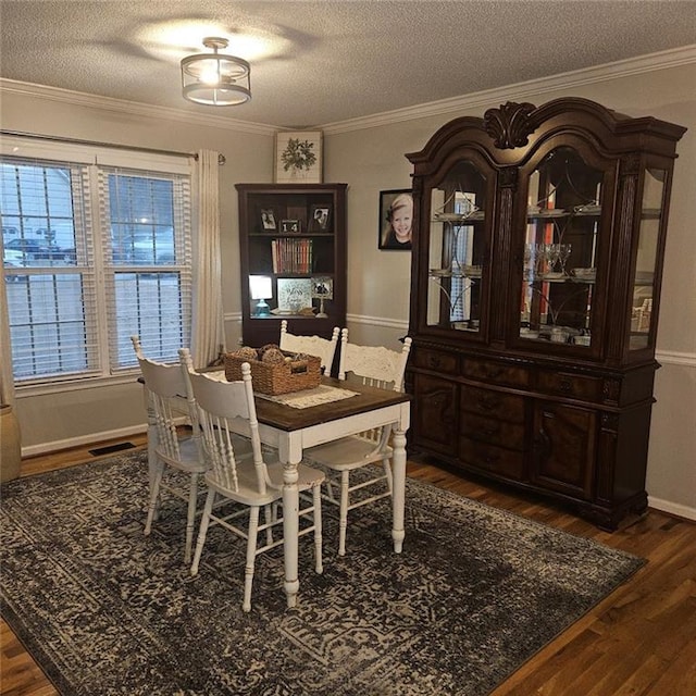 dining space featuring dark hardwood / wood-style flooring, ornamental molding, and a textured ceiling