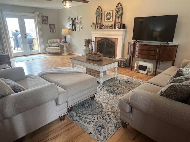 living room featuring wood-type flooring, ceiling fan, and french doors