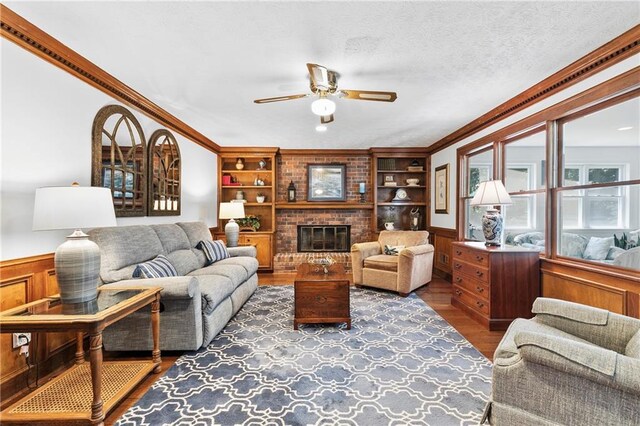 4875 Rivercliff Trce SW, Lilburn, GA 30047 - living room featuring wood finished floors, ceiling fan, built in features, a wainscoted wall, and a brick fireplace