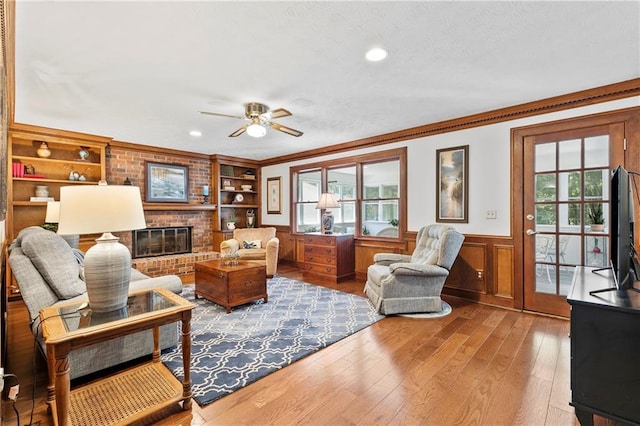 4875 Rivercliff Trce SW, Lilburn, GA 30047 - living area featuring wood-type flooring, healthy amount of natural light, wainscoting, a fireplace, and ceiling fan