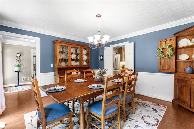 4875 Rivercliff Trce SW, Lilburn, GA 30047 - dining area featuring a chandelier, wood finished floors, ornamental molding, and wainscoting