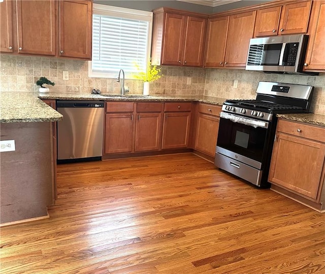 10175 Hemlock Way, Jonesboro, GA 30238 - kitchen featuring stainless steel appliances, a sink, light wood-type flooring, light stone counters, and brown cabinetry