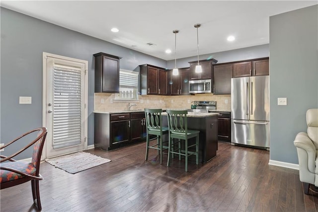 4746 Highland Ave, Sugar Hill, GA 30518 - kitchen featuring appliances with stainless steel finishes, dark brown cabinetry, a center island, tasteful backsplash, and recessed lighting