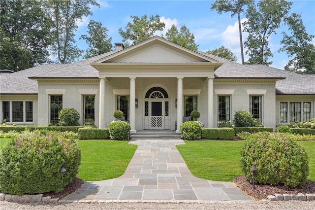 neoclassical home featuring a front lawn and a porch