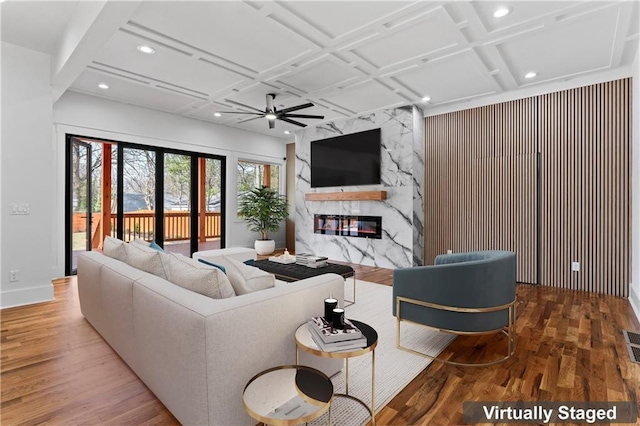 living area featuring coffered ceiling, a ceiling fan, wood finished floors, a high end fireplace, and visible vents