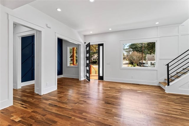unfurnished living room with baseboards, stairway, wood finished floors, and recessed lighting