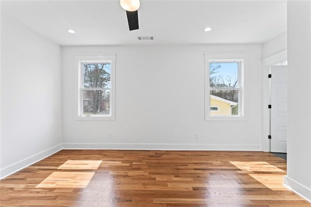 spare room with baseboards, wood finished floors, and plenty of natural light