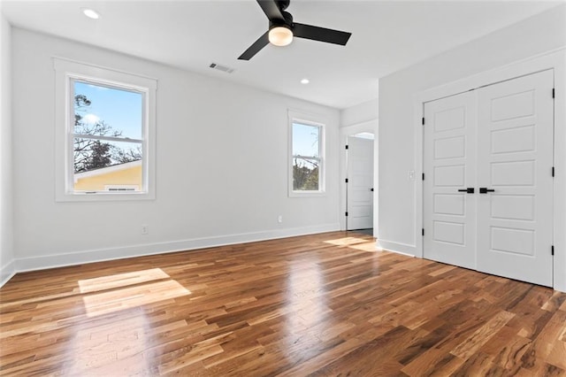 unfurnished bedroom with a closet, visible vents, baseboards, wood finished floors, and recessed lighting