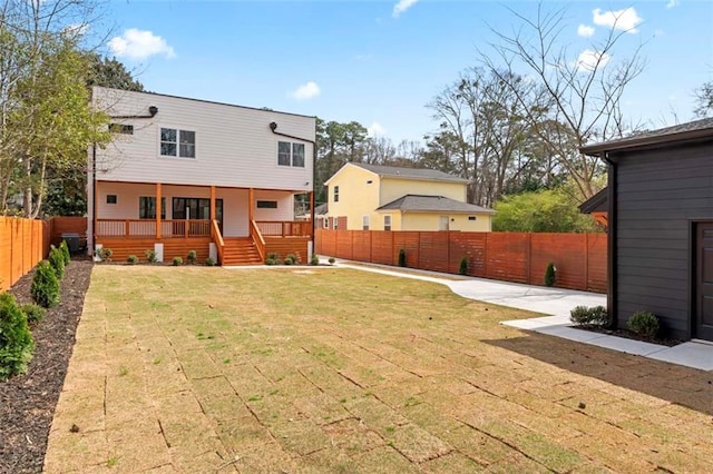 rear view of property featuring a fenced backyard, a deck, a yard, and a patio