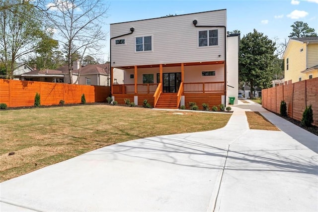 rear view of house with driveway, fence, and a yard